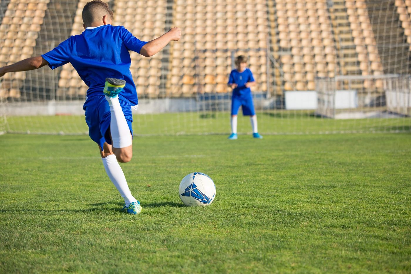 A boy striking a football in an empty stadium, the setting for the xGI academy programme