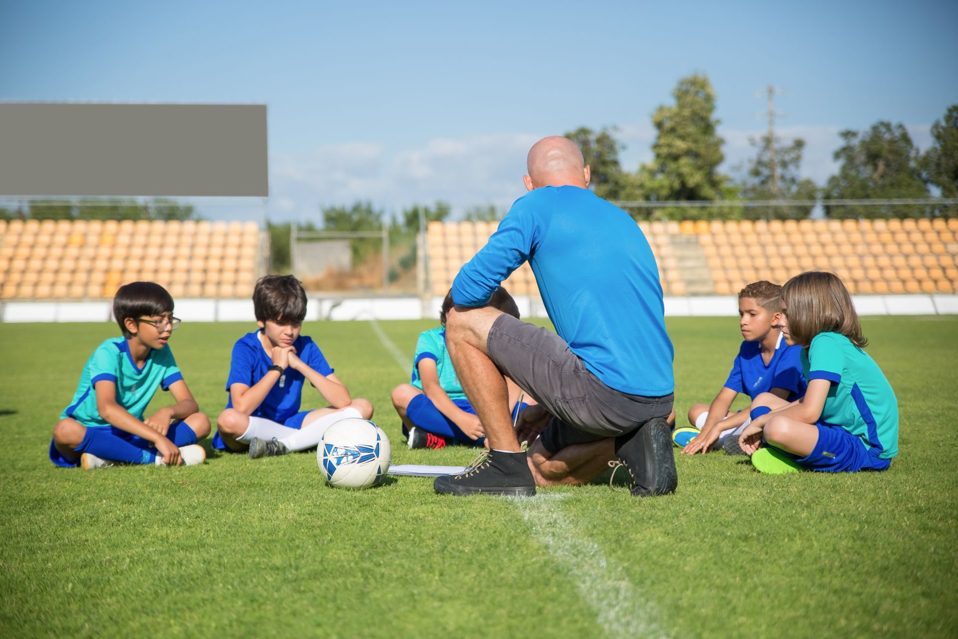 A coach sitting on the grass with a group of young players before a football session in Dublin